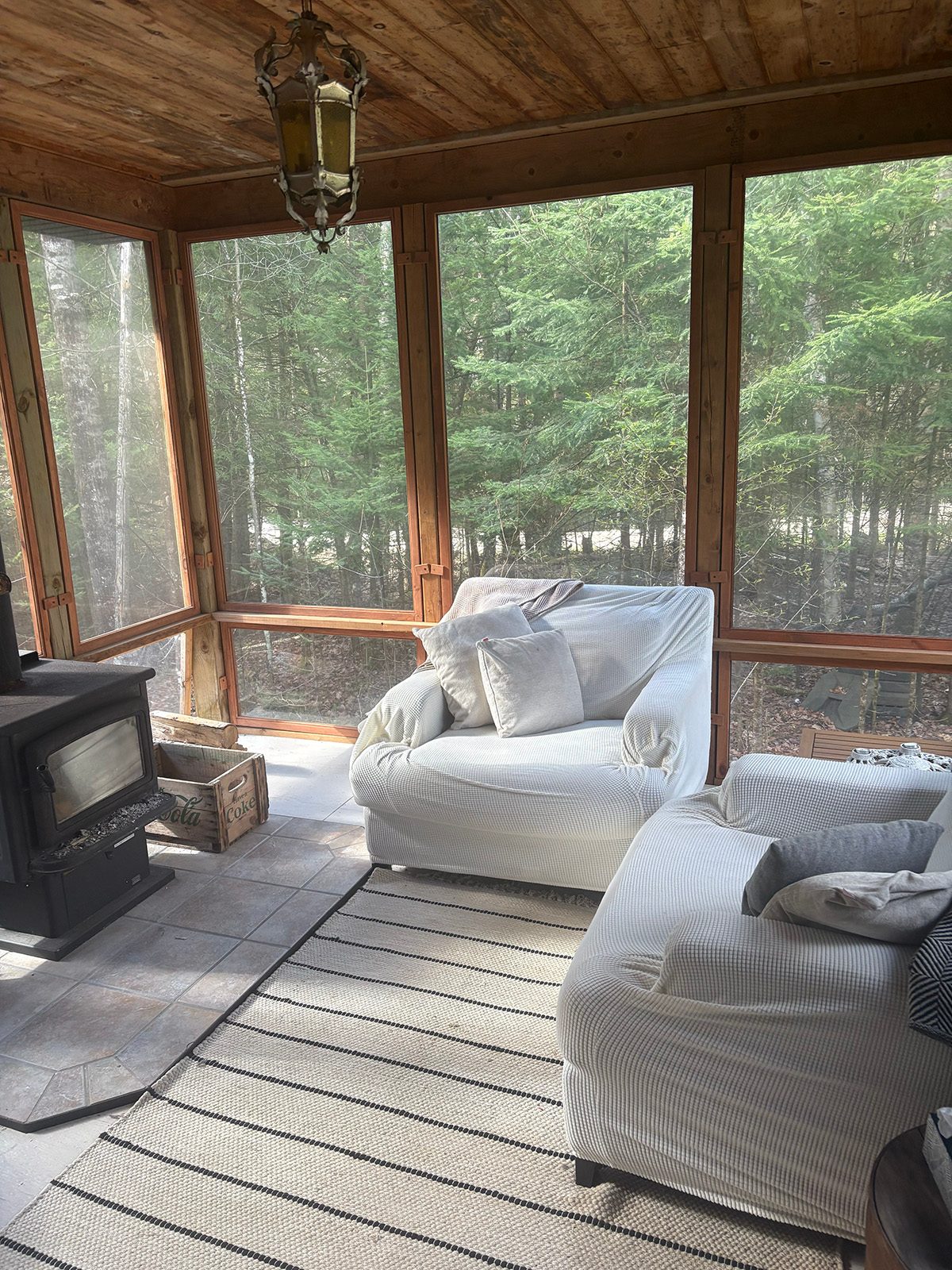 Two white armchairs facing each other beside large forest-facing windows.